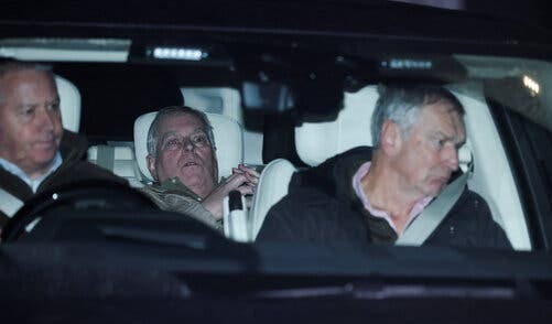Inside a vehicle, the former Prince Andrew has wide eyes and a slightly open mouth, hands clasped. A person in a dark jacket and another person are in the front.