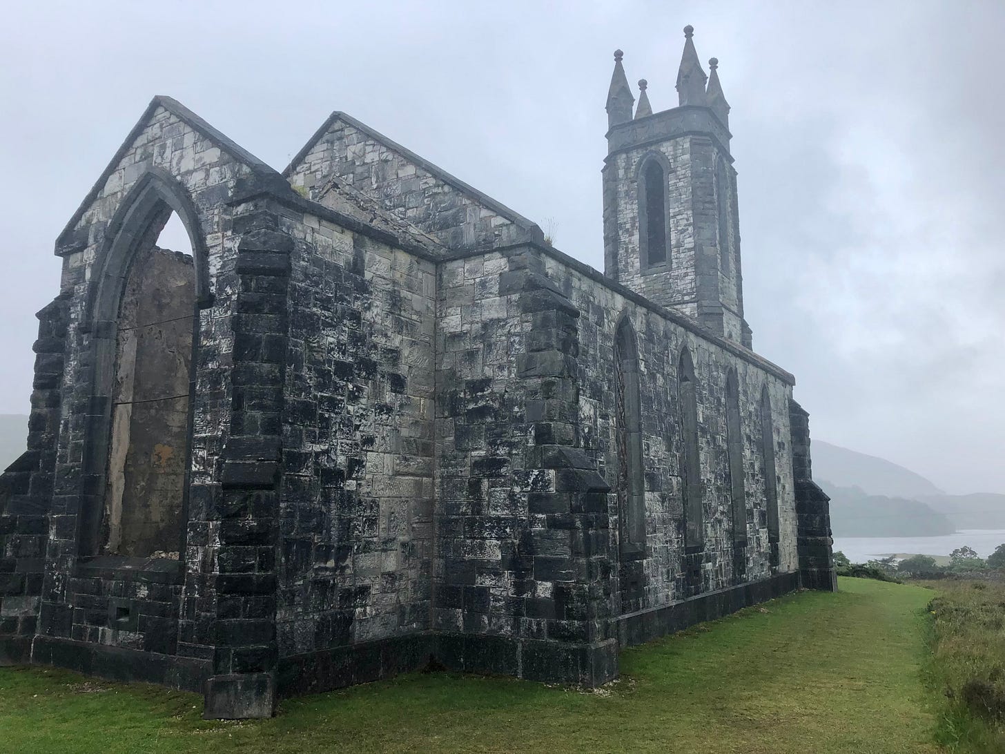 Ruined stone church at Dunlewey in County Donegal, Ireland, on a misty day with Mount Errigal in the background.