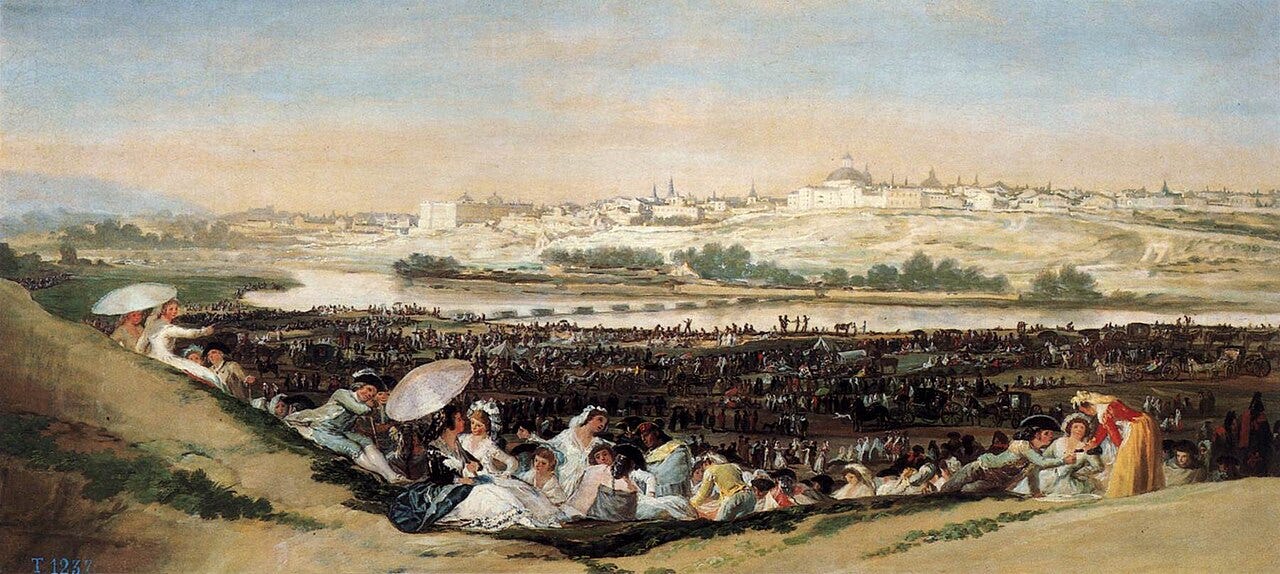 Crowds picnicking and dancing on a riverbank with the Madrid skyline behind Crowds picnicking and dancing on a riverbank with the Madrid skyline behind