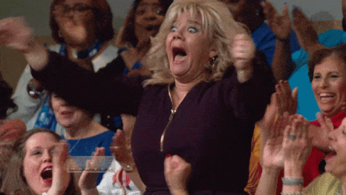 Woman standing and cheering as audience around her goes wild with applause
