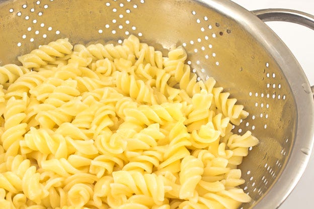 Fusilli pasta cooked al-dente’ draining in a colander. When cooked, drain the pasta, then rinse in cold water to bring the temperature down quickly, stopping the cooking process and keeping the noodles loose for the salad. Once cooled, transfer the cooled pasta to a colander or mesh strainer, shake to remove as much excess water as possible. Set aside for about 3 minutes to drain any additional water trapped. Fusilli pasta cooked al-dente’ draining in a colander. When cooked, drain the pasta, then rinse in cold water to bring the temperature down quickly, stopping the cooking process and keeping the noodles loose for the salad. Once cooled, transfer the cooled pasta to a colander or mesh strainer, shake to remove as much excess water as possible. Set aside for about 3 minutes to drain any additional water trapped.