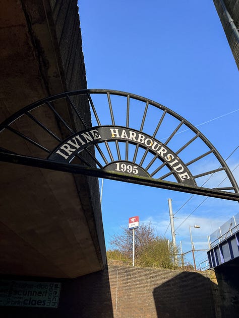 L to R: A close up of empty, deep brown stained wall shelves, a cast iron sign for Irvine Harbourside against a bright blue sky at the Irvine train station, a close up of worn wooden floors needing some TLC.