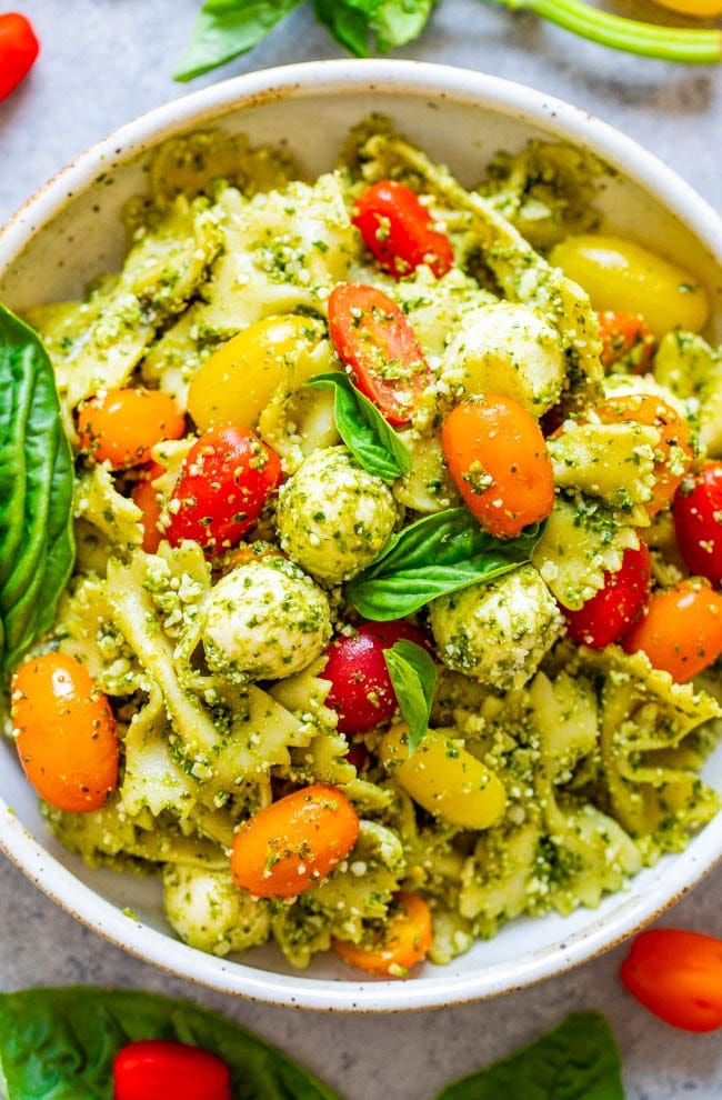Tomato and Mozzarella Pesto Pasta Salad - Tender pasta, cherry tomatoes, and fresh mozzarella are coated in Parmesan cheese and DELICIOUS pesto sauce!! EASY, ready in 15 minutes, and great for easy meals with planned leftovers or for parties because it feeds a crowd!!