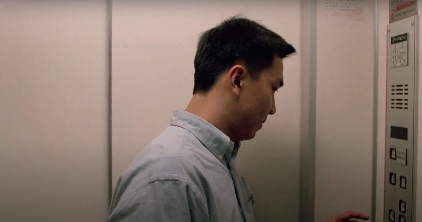 Ming stands inside an elevator with the door closed and stares at the control pad in Edward Yang's movie A Confucian Confusion.