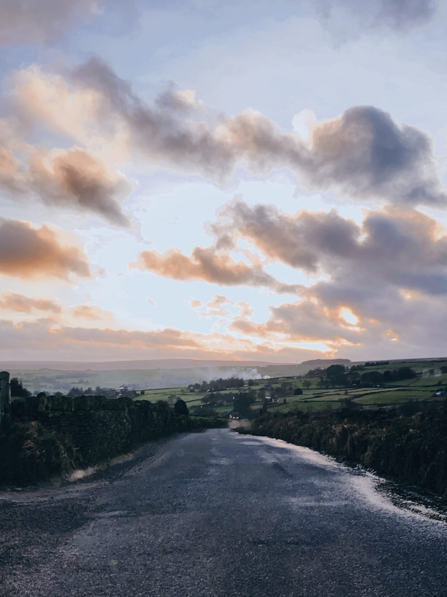 looking down a curving yorkshire lane with an expansive sky at sunset.