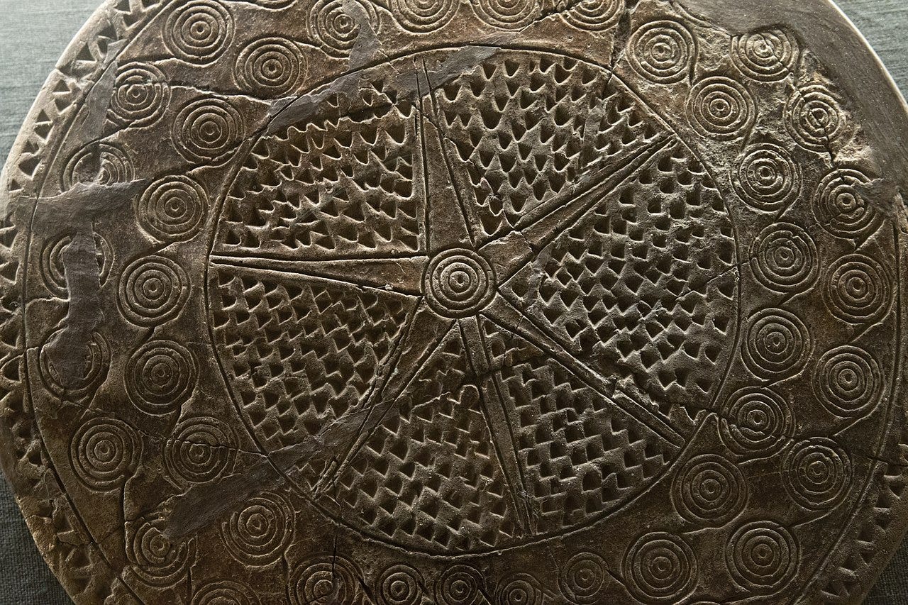 Drum-shaped terracotta funerary vessel from a Cycladic grave on the Aegean island of Syros. The side facing the camera is engraved with a large star surrounded by small dots and rings of concentric circles.