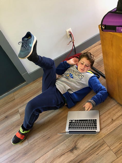 kid sitting at a desk doing math, kid lying on the floor with a laptop doing situps, three kids holding a microphone and recorder, interviewing a stuffed bear