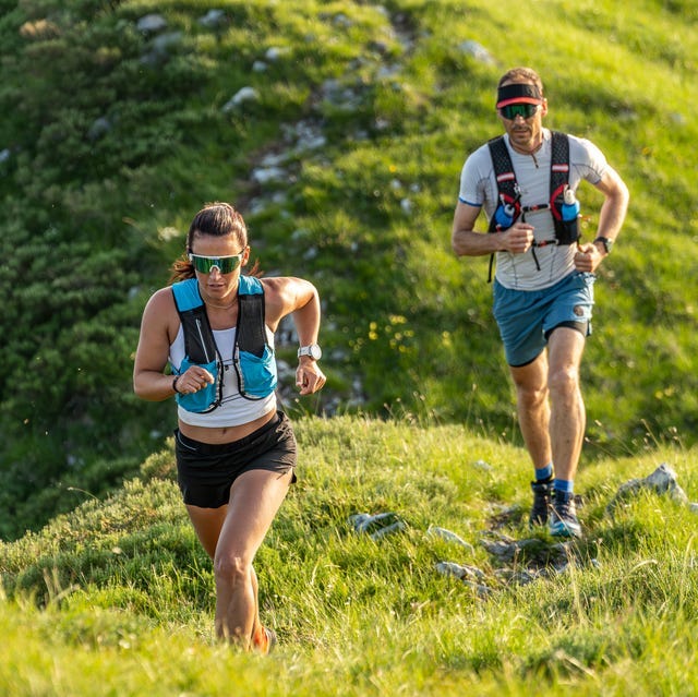 Two Runners in Athletic Gear on a Grassy Hillside two runners in athletic gear on a grassy hillside