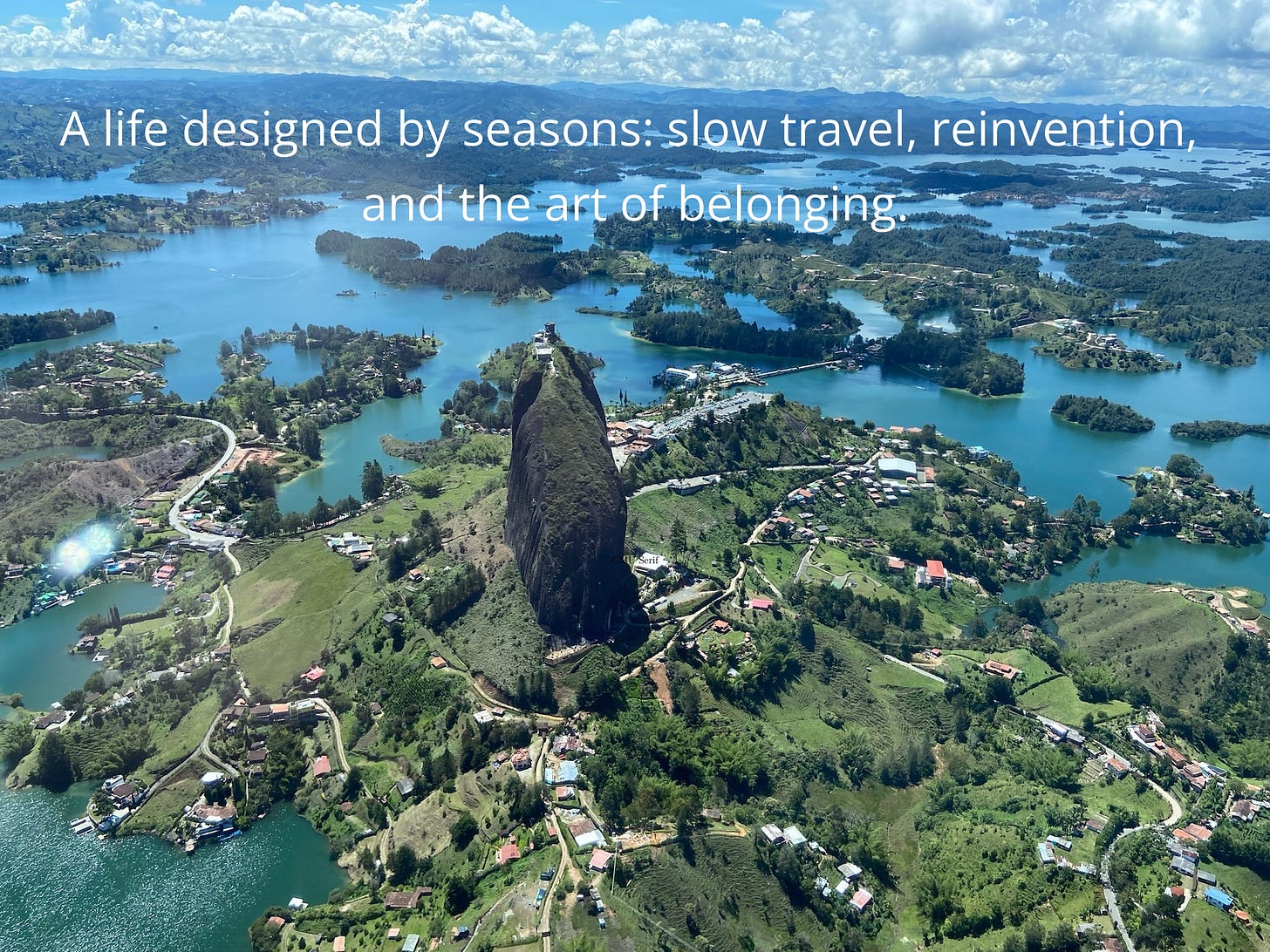 Aerial view of Guatapé, Colombia, with lakes, green hills, and the Piedra del Peñol rock formation under a clear sky — used to illustrate the idea of designing a life by seasons through slow travel.