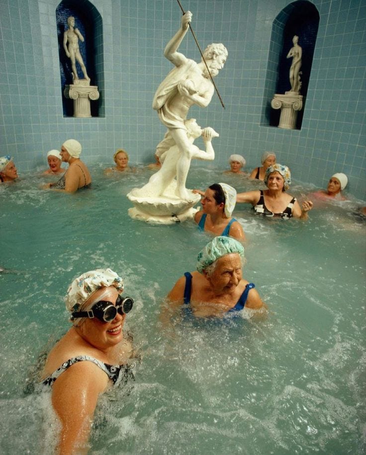 This may contain: several people in a large swimming pool with statues