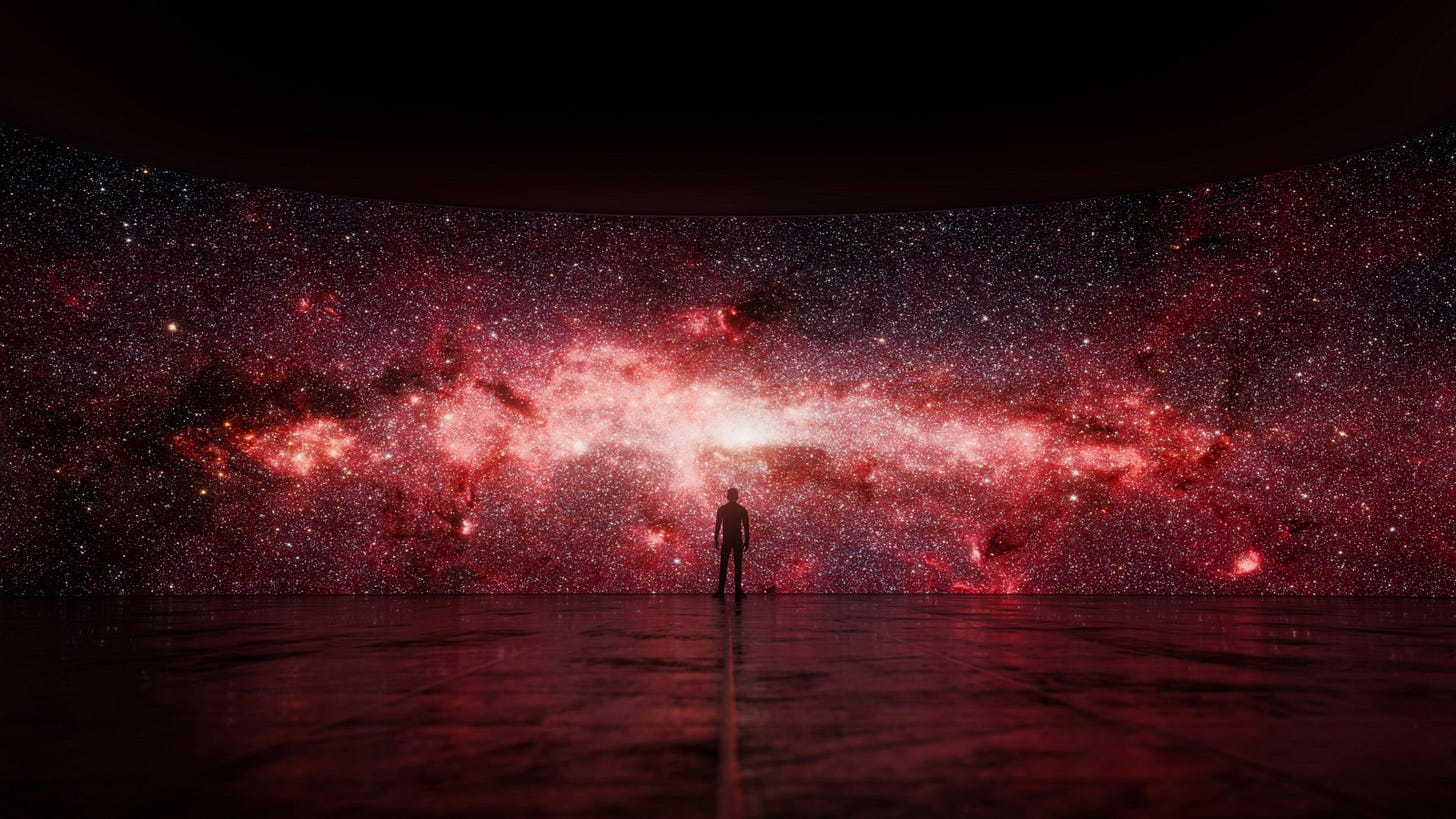 A man stands in front of galaxies and stars
