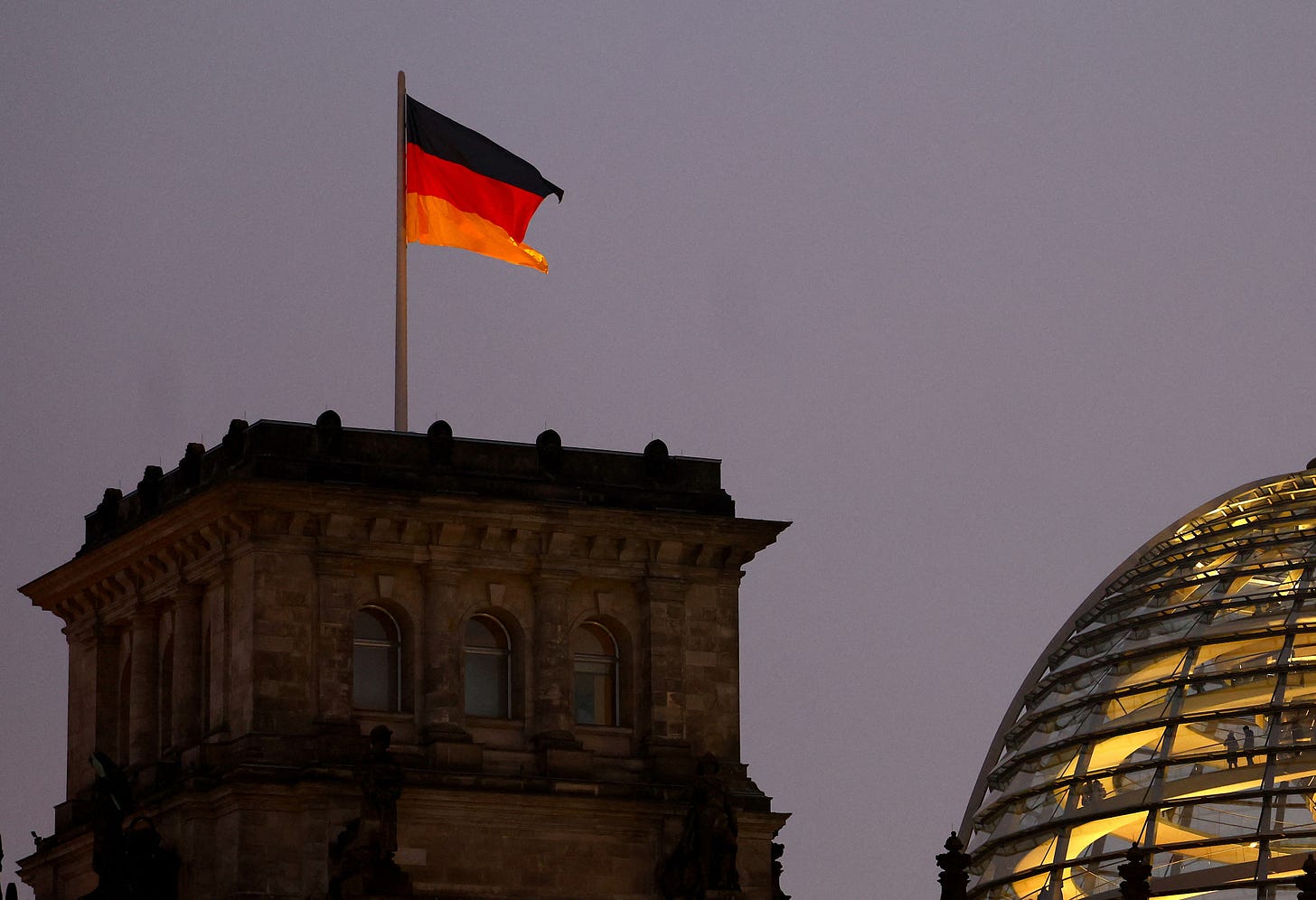 A German national flag flies atop the illuminated Reichstag building in Berlin A German national flag flies atop the illuminated Reichstag building in Berlin