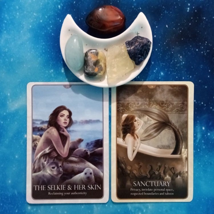 Two Oracle of the Mermaids cards and crystals on a starry blue background