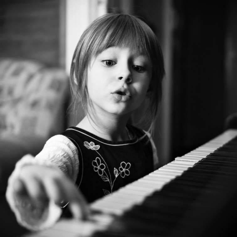 May be a black-and-white image of child and piano