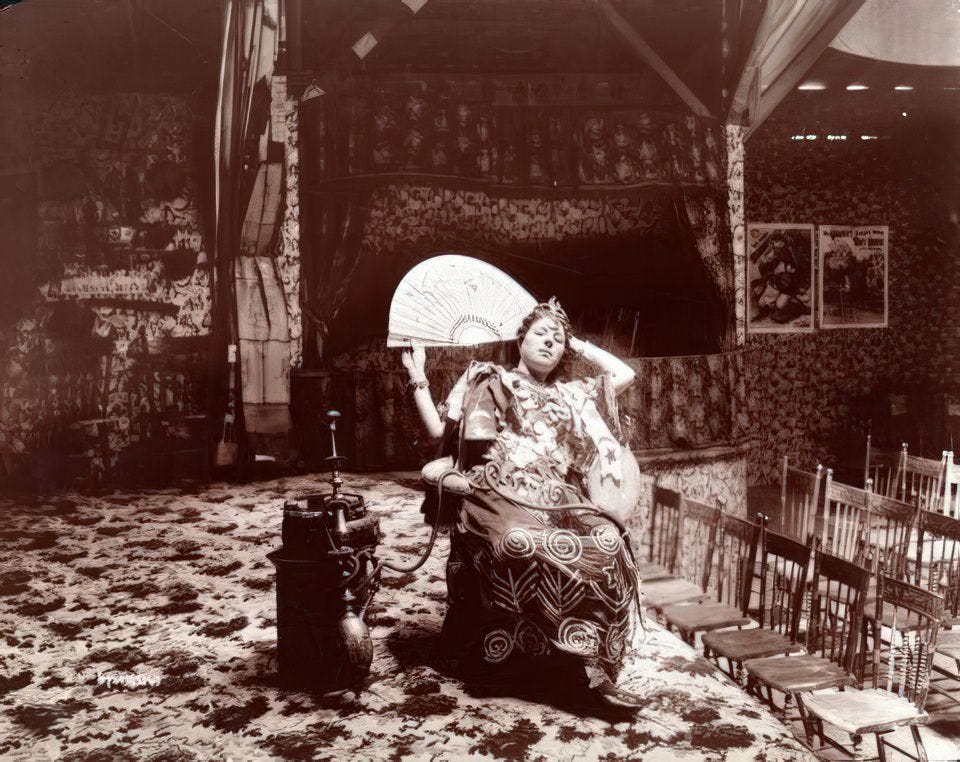 Woman gypsy/dancer seated in her side-show theatre at Coney Island, 1896.