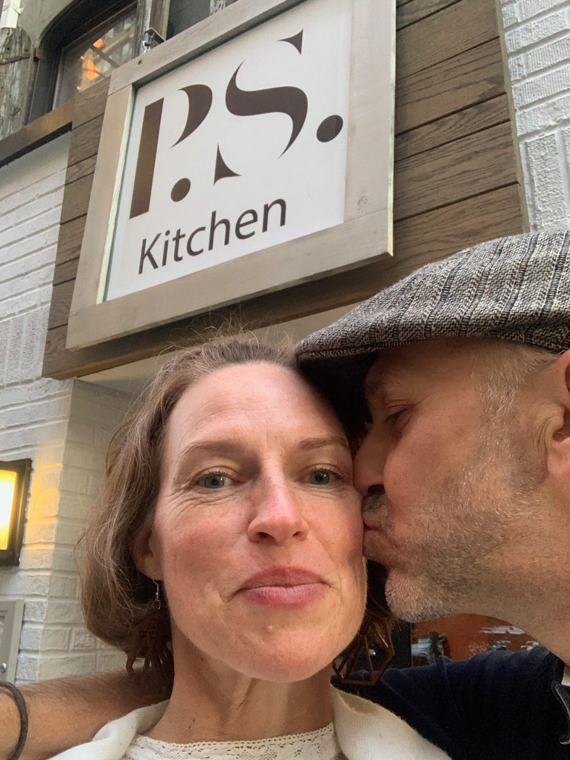 Paul giving Christina a kiss on the cheek in front of P.S. Kitchen