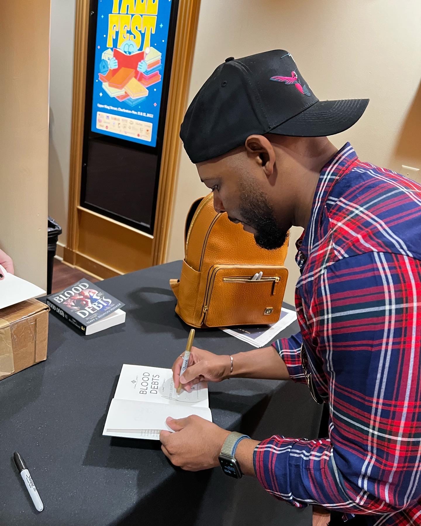A photo of me signing an ARC of Blood Debts