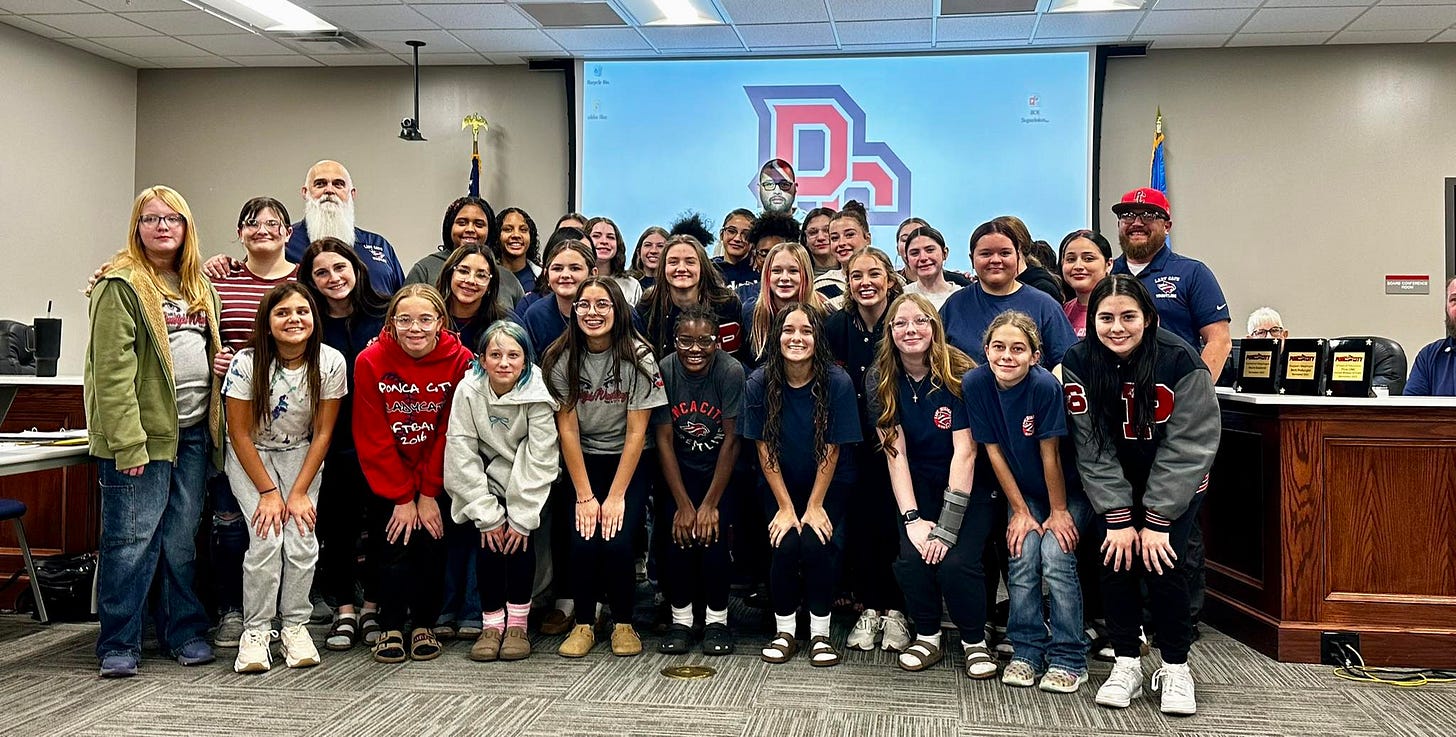 A group of people, including both men and women, are posing for a picture in front of a screen. A group of people, including both men and women, are posing for a picture in front of a screen.