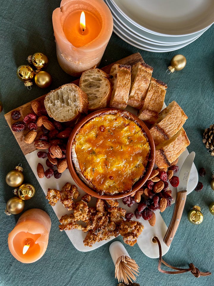 Two different preparations of Camembert shown with nuts, dried fruits and baguette bread
