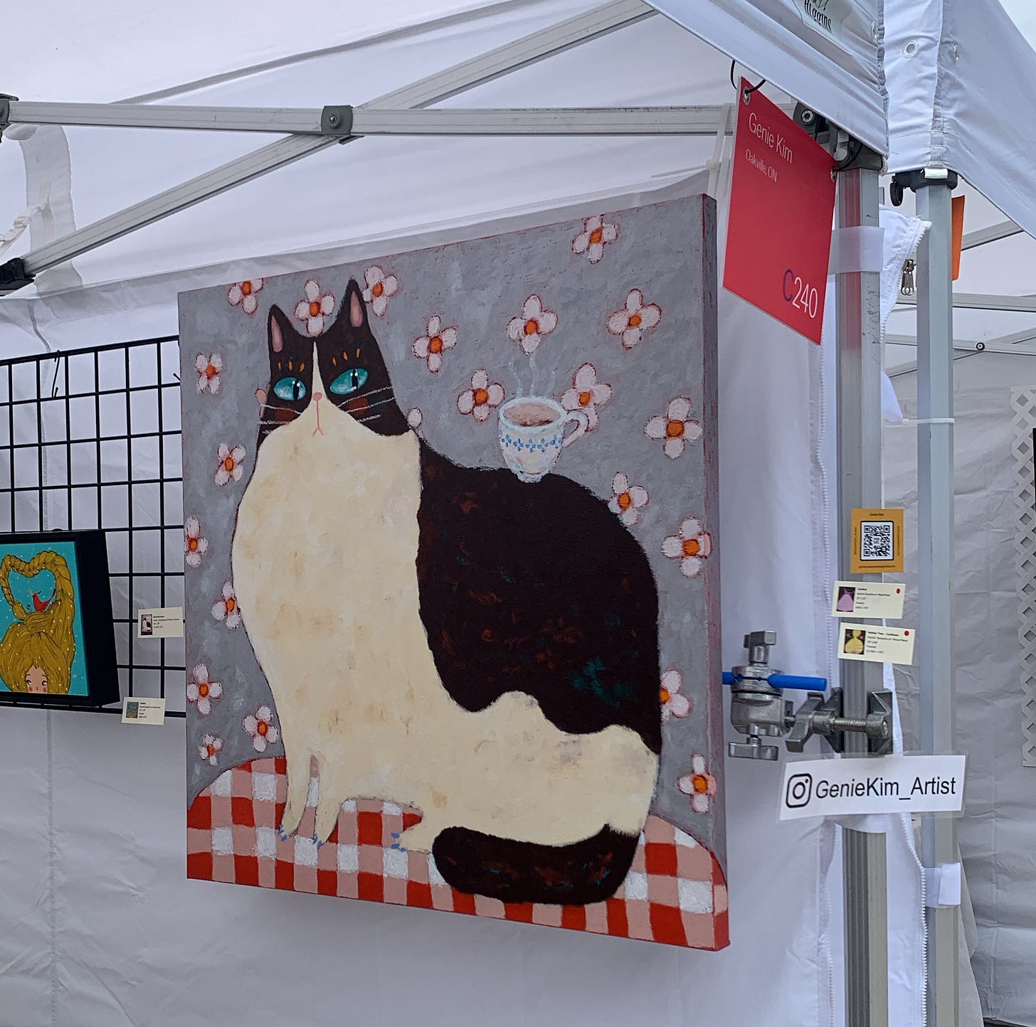 A painting of a very large cat with blue eyes and pink eyelashes, looking inquisitively at a cup of coffee that sits on its back.