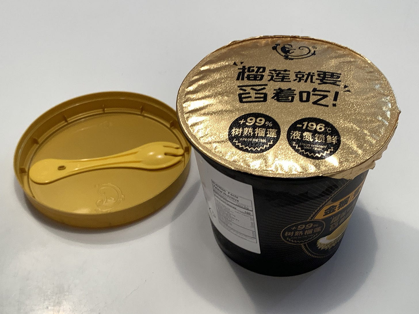 Lid removed from the cup revealing foil liner and disposable spork-looking utensil