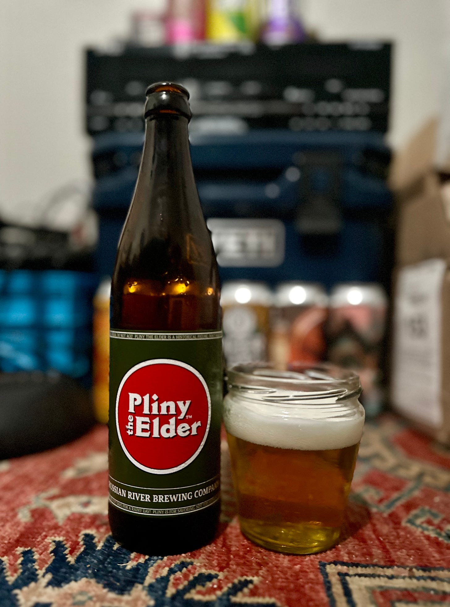 A bottle of Pliny The Elder beer next to a mason glass with the beer in it