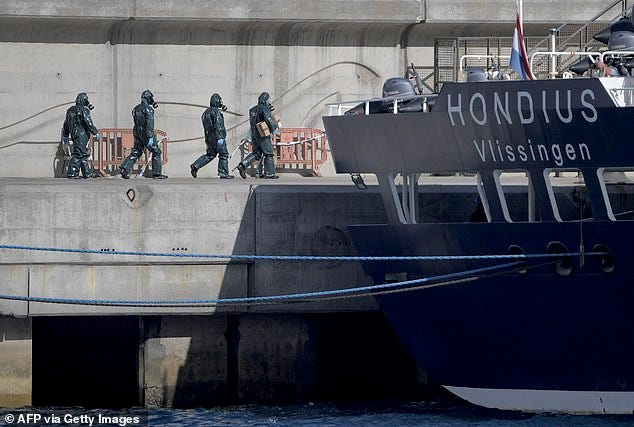 Persons wearing protective suits walk toward the hantavirus-stricken cruise ship MV Hondius docked in the port of Granadilla de Abona on the island of Tenerife in Spain's Canary Islands on May 11