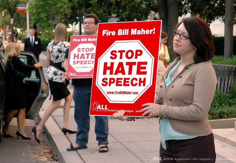 Members of the American Life League, a conservative Catholic organization, protest comedian Bill Maher for allegedly promoting anti-religious speech. The call to 'Stop Hate Speech'—here used against secular criticism—illustrates how the term has become a tool claimed across ideological lines, shaped less by content than by contested moral frameworks.