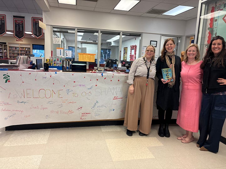 Shana Youngdahl with a sign that says "Welcome Shana Youngdahl" painted with flames, tiny gnomes ontop of the book A Catalog of Burnt Objects by Shana Youngdahl, Shana Youngdahl with a cart of books to sign for students, Shana Youngdahl with the library and a teacher from Centennial High