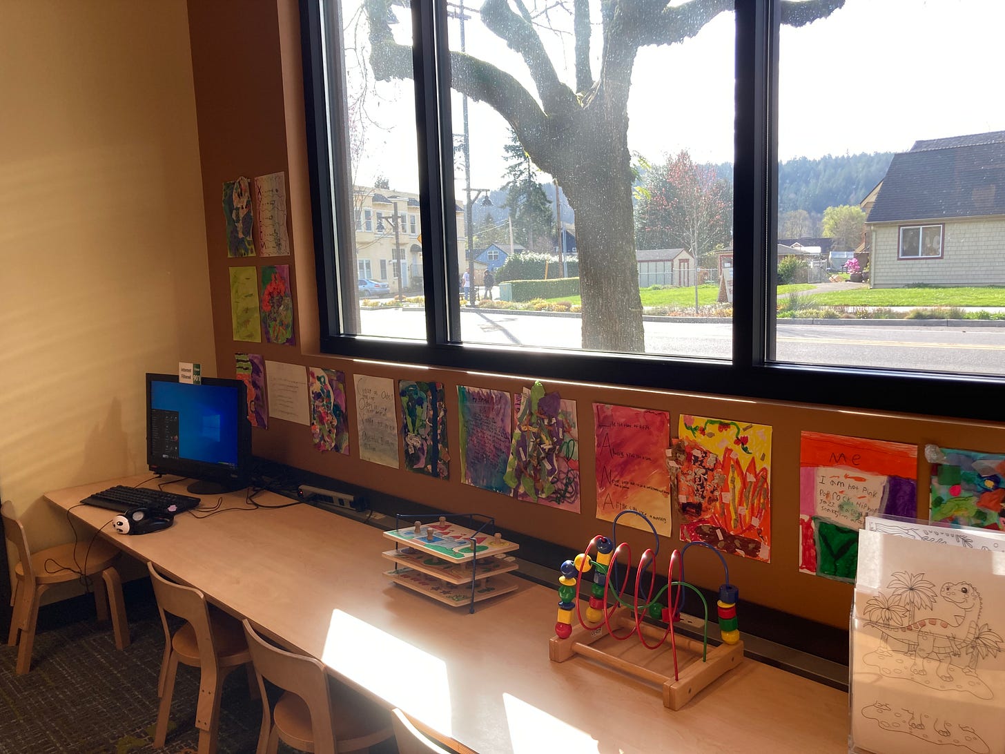 The children's area of the library, with art posters on the wall and a window with a tree in it.