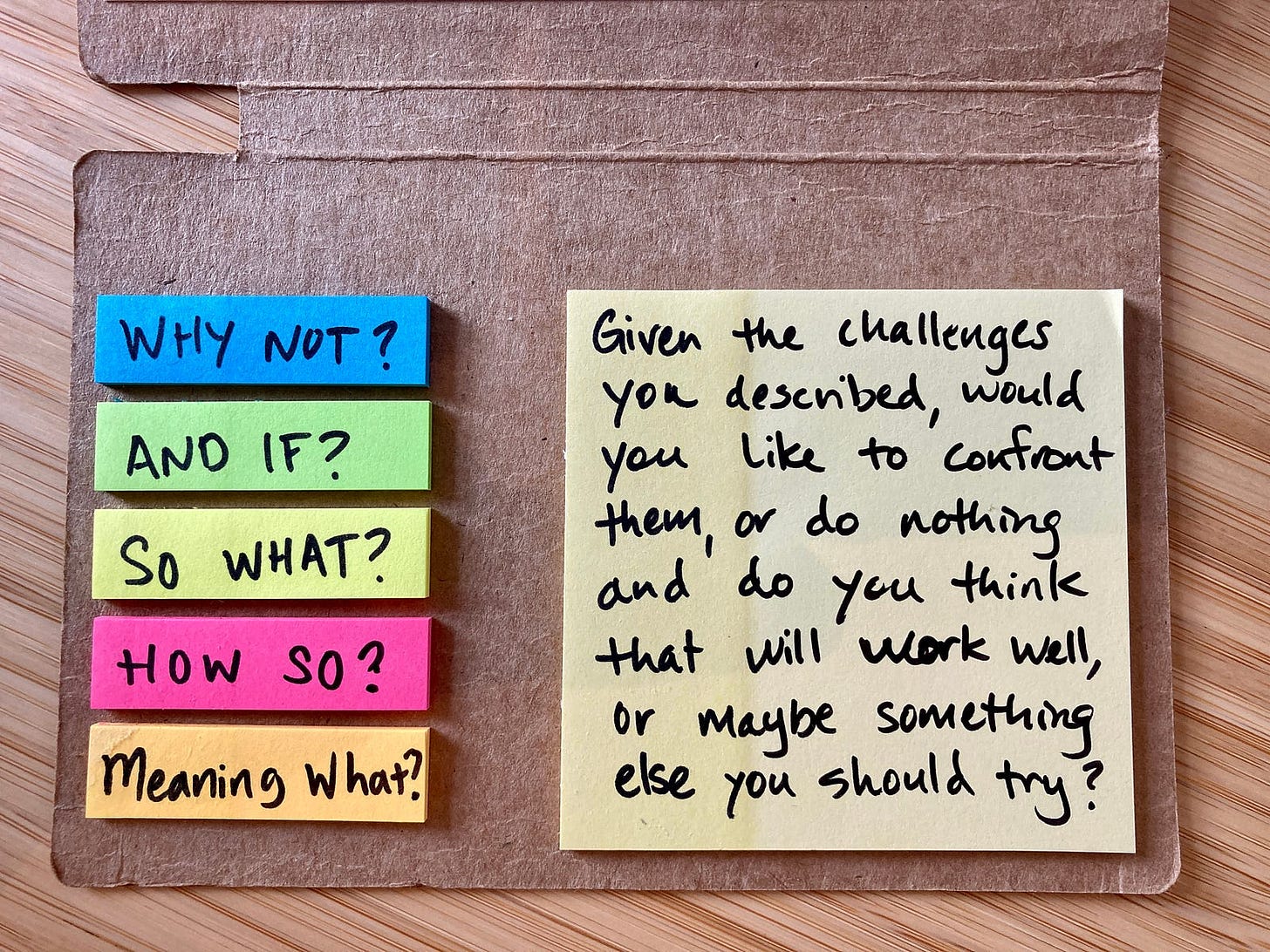 A small notebook with stickies. The small stickies on the left have short two-word questions on them; the large sticky note on the right has a long, rambling, compound question that makes the person think too hard.