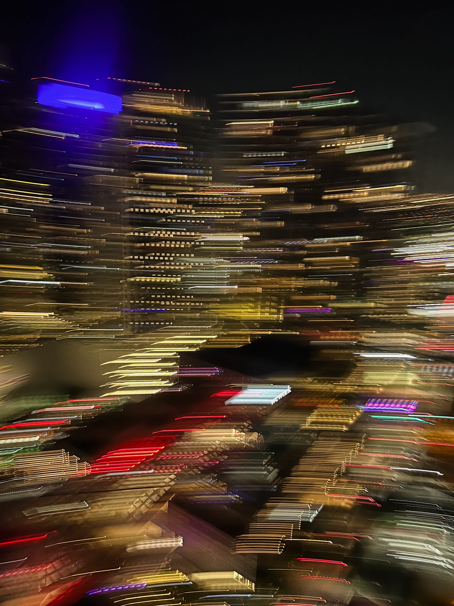 Blurred, shaky photo of multicolored lights from high-rise buildings in a downtown area