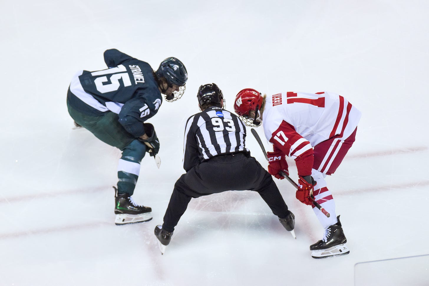 College hockey centers for the Michigan State Spartans, Charlie Stramel, and Wisconsin Badgers, Grady Deering, stand at a faceoff dot in Wisconsin's defensive zone waiting for an official to drop a puck College hockey centers for the Michigan State Spartans, Charlie Stramel, and Wisconsin Badgers, Grady Deering, stand at a faceoff dot in Wisconsin's defensive zone waiting for an official to drop a puck