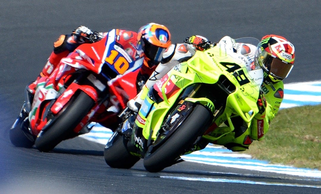 Motorcyclists race on a track during a competition.