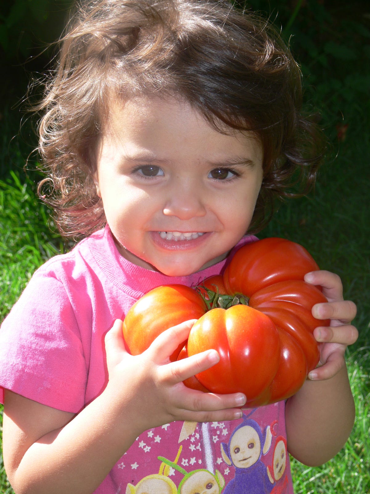 a young girl holding a tomato