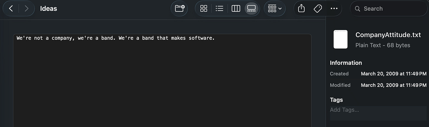 A dark-mode screenshot of a text file titled "CompanyAttitude.txt," open in a file browser, reading: "We're not a company, we're a band. We're a band that makes software." Created and modified March 20, 2009.