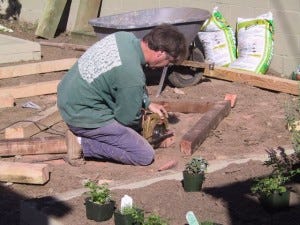 C cuts wood for a diamond-shaped bed.