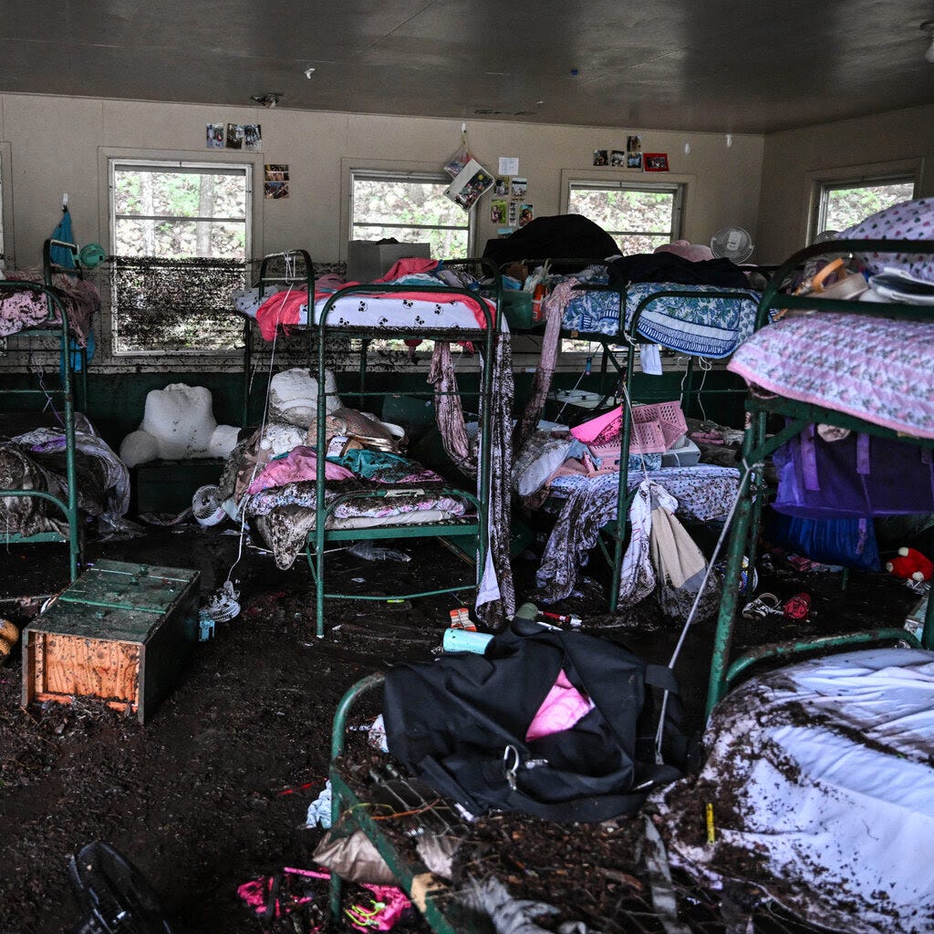 A cabin with bunk beds and possessions covered in mud. 