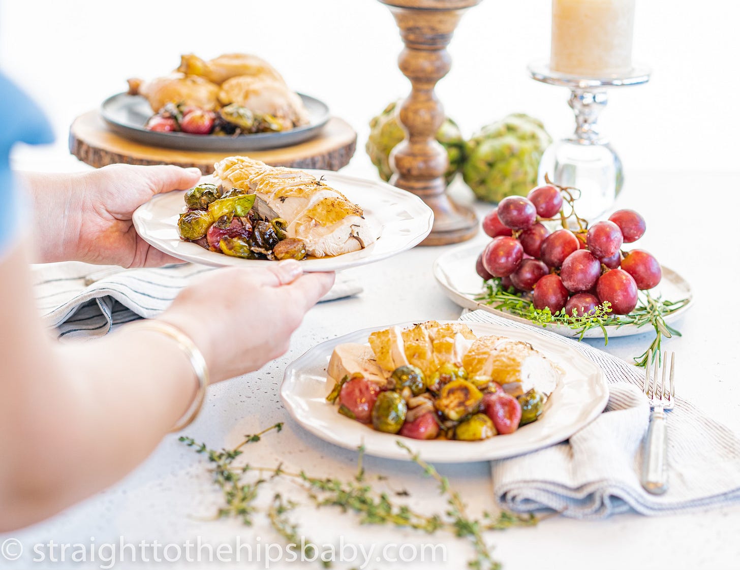  Sliced roasted chicken with thyme plated and served at a dinner table with candles