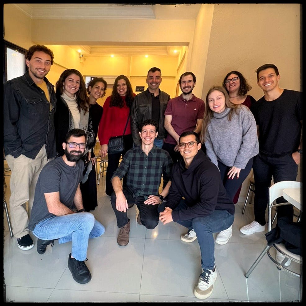 Imagem de 9 pessoas em pé ao fundo e 3 pessoas de joelhos na frente. Todos são os participantes da primeira roda de conversa presencial sobre dinheiro em São José dos Campos, SP