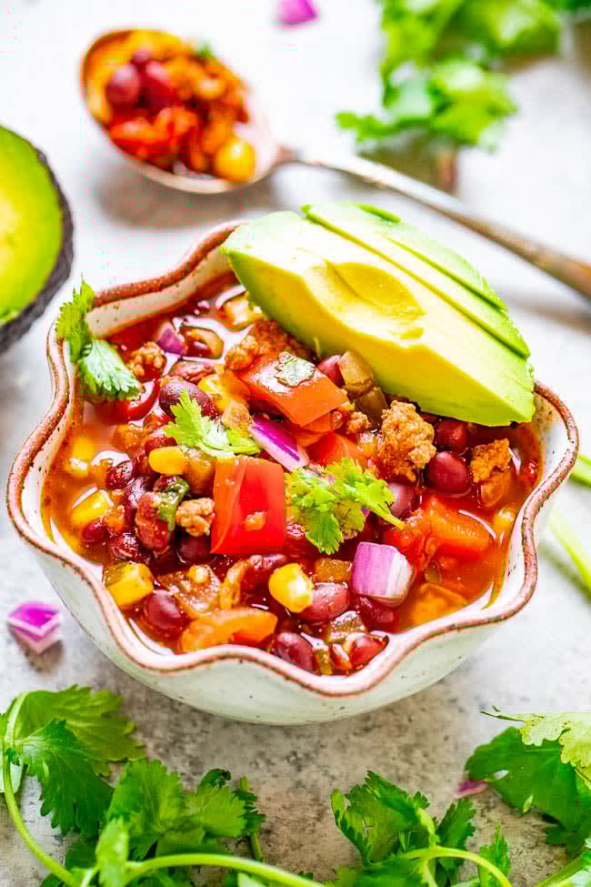 A bowl of taco soup topped with avocado slices. 