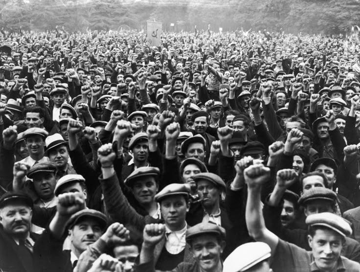 This may contain: a large group of people standing next to each other in front of a crowd with their hands up