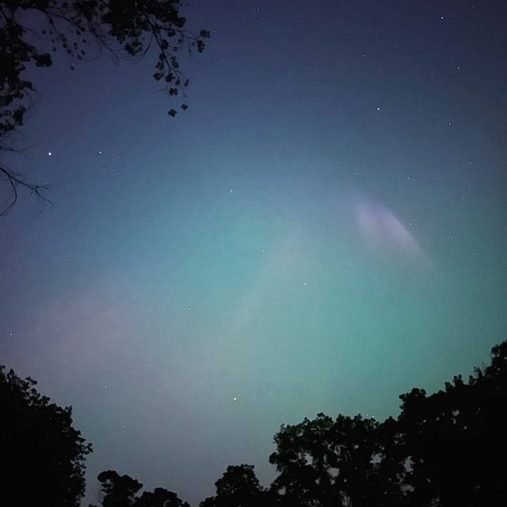 Two images of lights in the sky; the first shows faint blue, green and pink ribbons of light from the aurora borealis. The second image shows a road winding through Badlands National Park, lit by vehicle headlights.