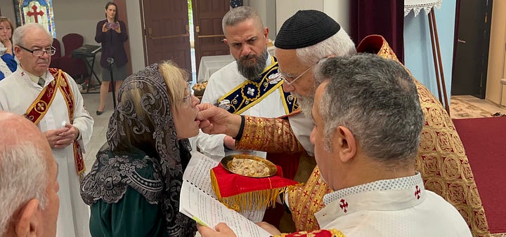A priest blessing a woman and giving her communion