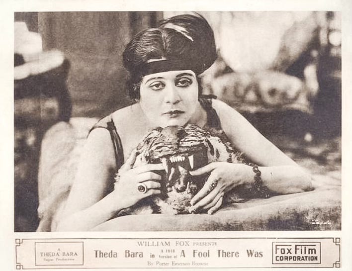Promotional photo for the 1915 film “A Fool There Was” features Theda Bara lounging on a tiger skin rug. She rests her chin on its stuffed head and idly toys with one of its bared fangs.