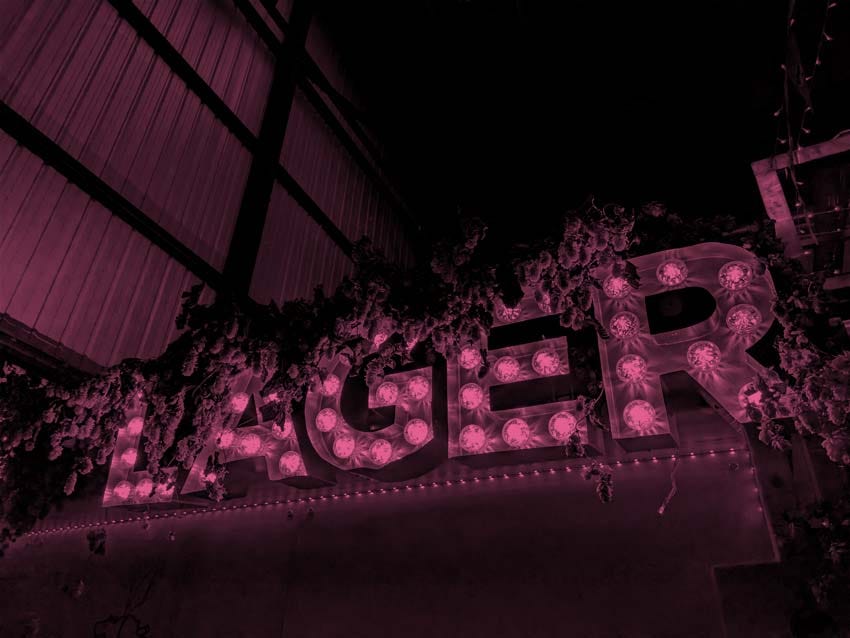 An illuminated sign reading LAGER at Lost & Grounded's taproom.