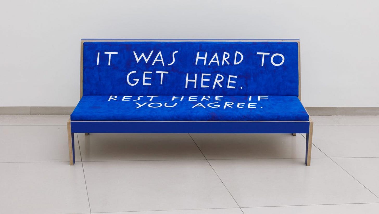 Blue couch that says "It was hard to get here, rest here if you agree." Blue couch that says "It was hard to get here, rest here if you agree."