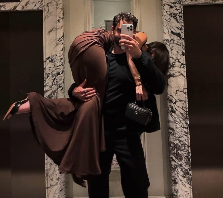 This may contain: a man and woman taking a selfie in front of an elevator with their arms around each other This may contain: a man and woman taking a selfie in front of an elevator with their arms around each other