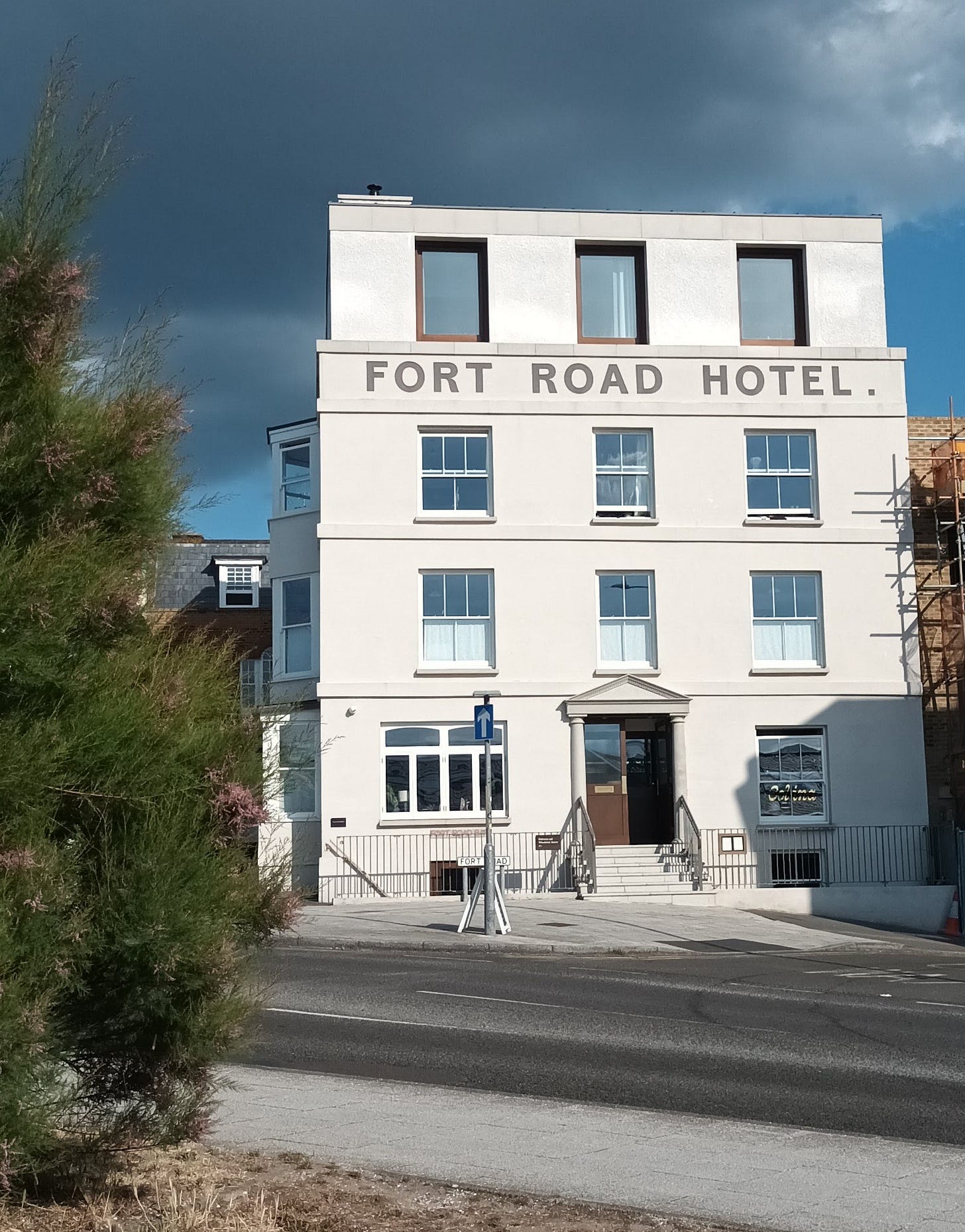 A four story white building with "Fort Road Hotel" written on the front