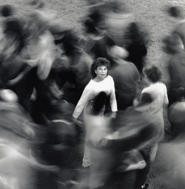 This may contain: a black and white photo of a woman surrounded by other people in motion blurry